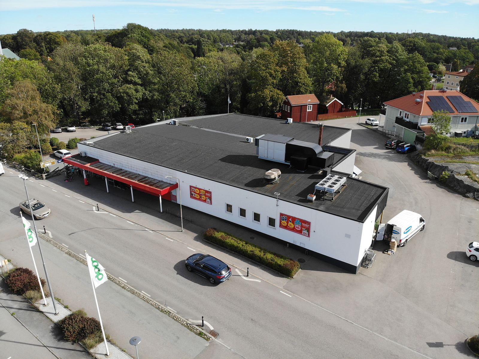 Butiksfastigheten på Sölvesborgsvägen 34 i Mörrum sedd från luften, med det röda skärmtaket över entrén mot gatan, lastintaget på gaveln och parkeringen runt om.